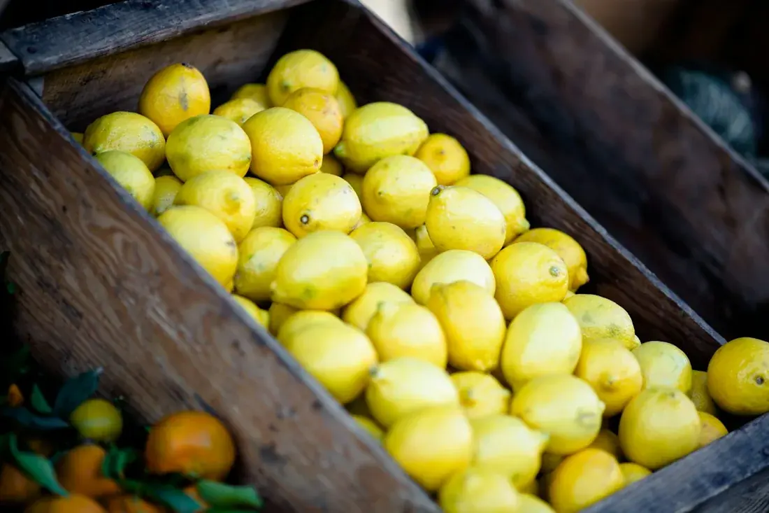 Yellow lemons displayed in a wooden produce crate.