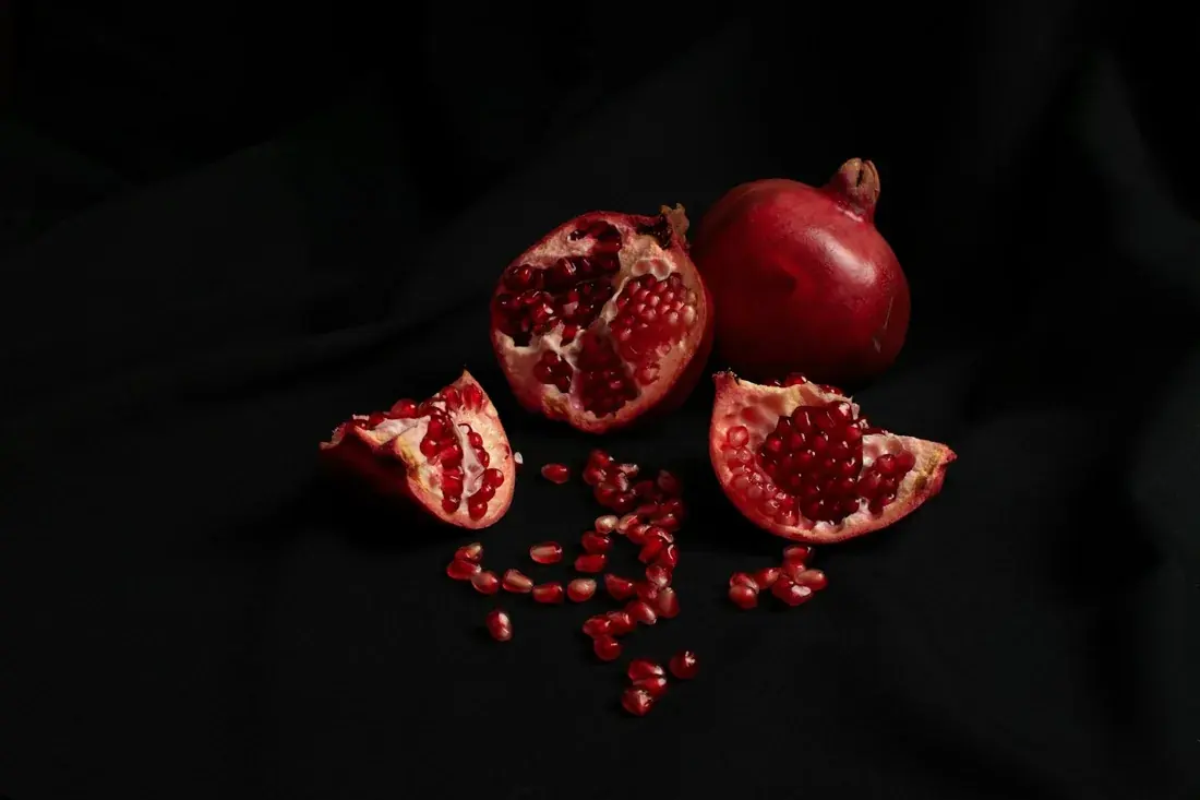 Whole and opened pomegranates on a dark background.