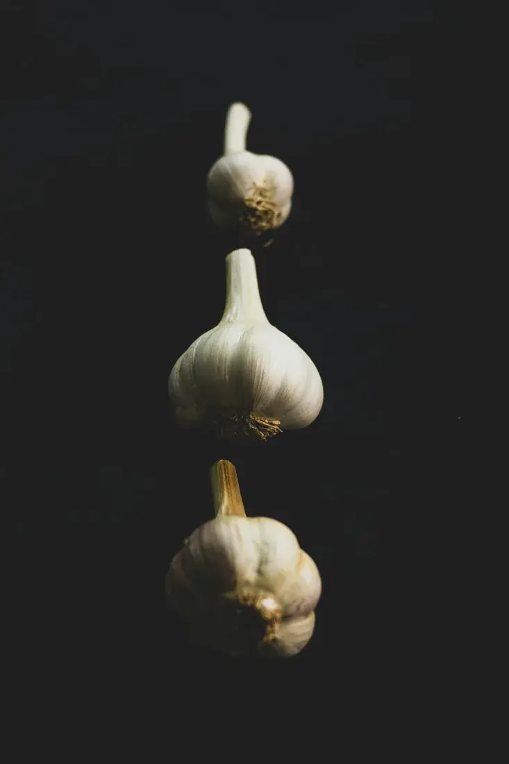 Whole garlic bulb with one clove on a dark surface